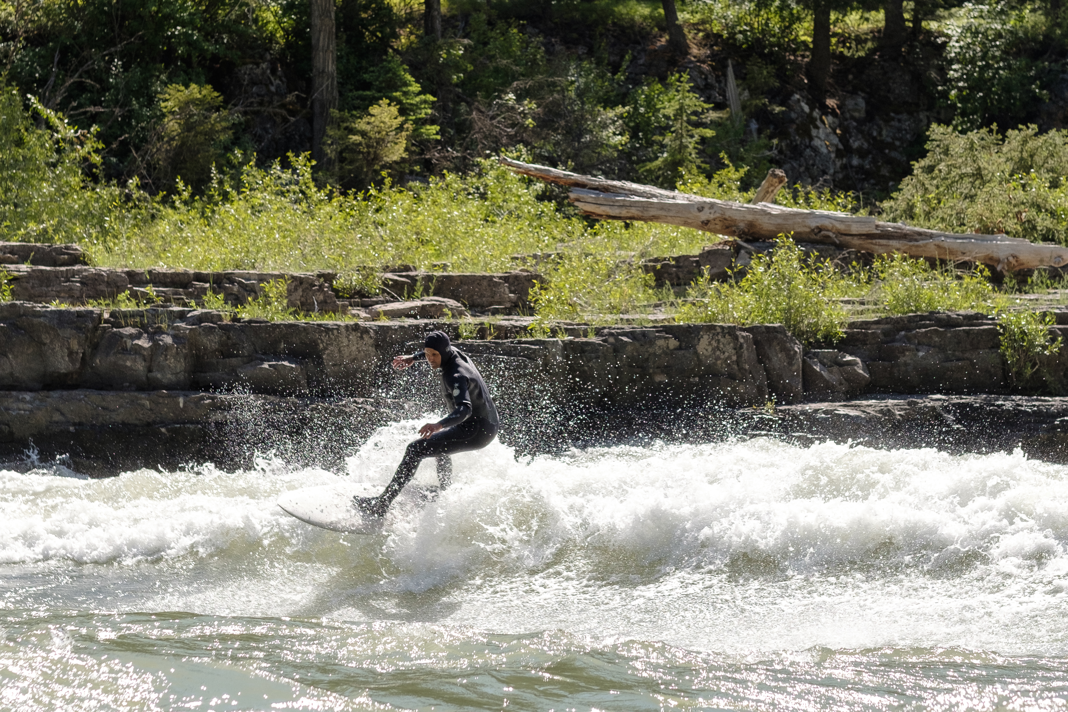 Surfer riding a wave on Snake River in bright sunlight