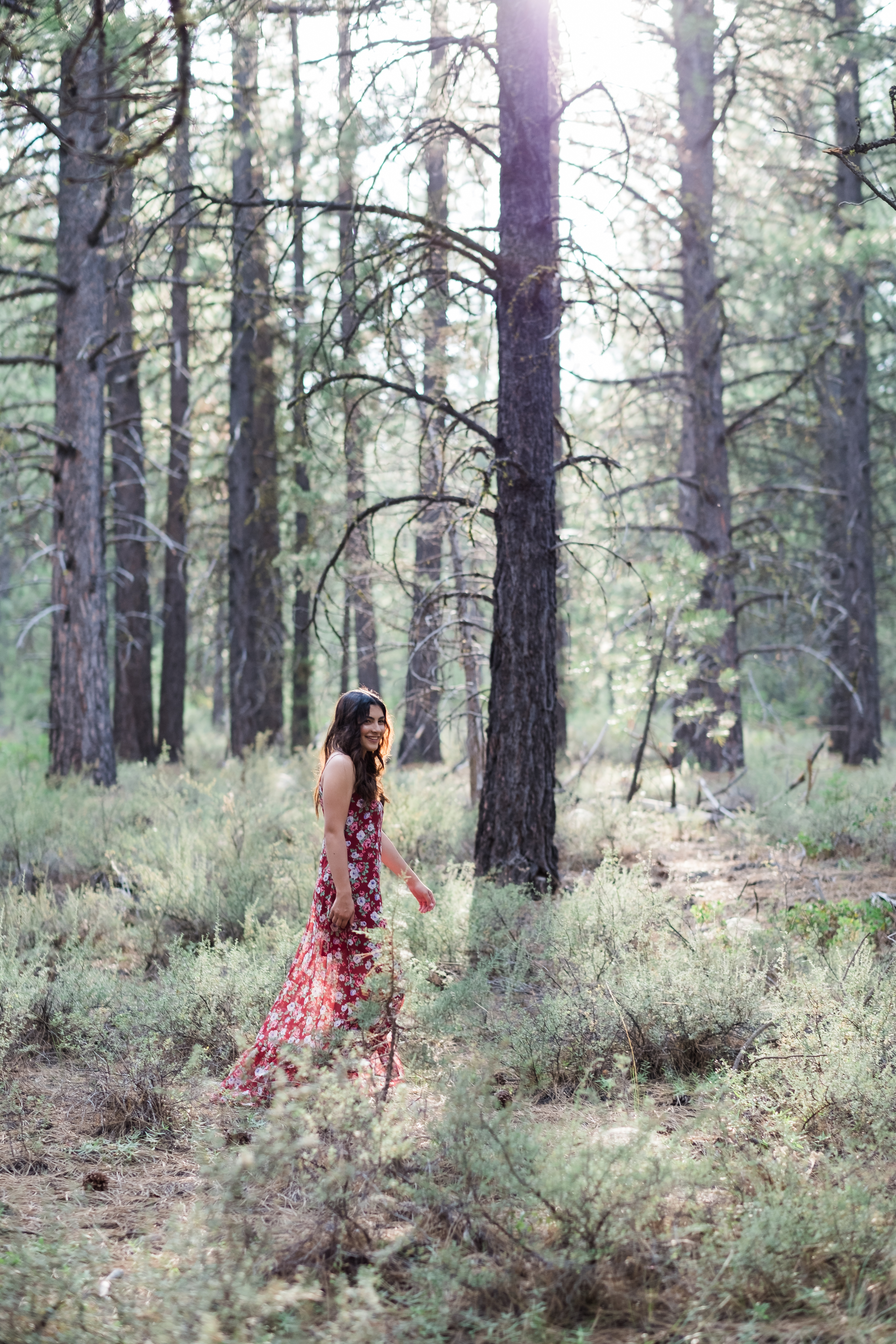Woman in a deep plum dress standing in a softly lit forest